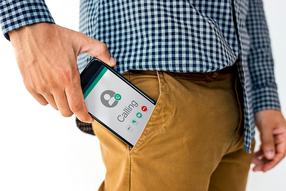 Hand holding network graphic overlay digital device in trouser pocket