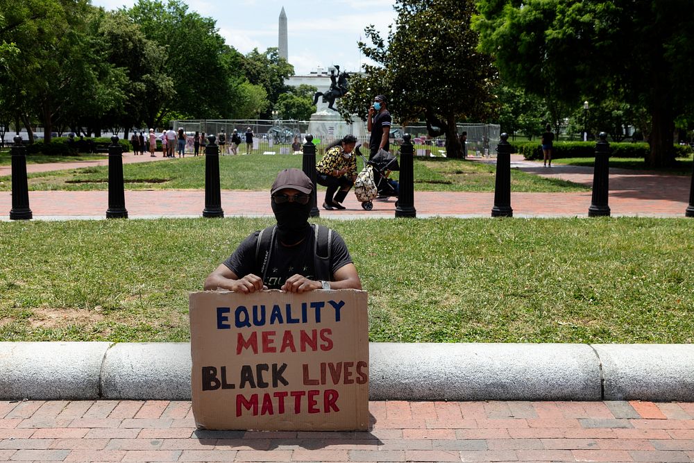                         Abillah Barry Ichingwah poses with a Black Lives Matter sign on Lafayette Square across from the…