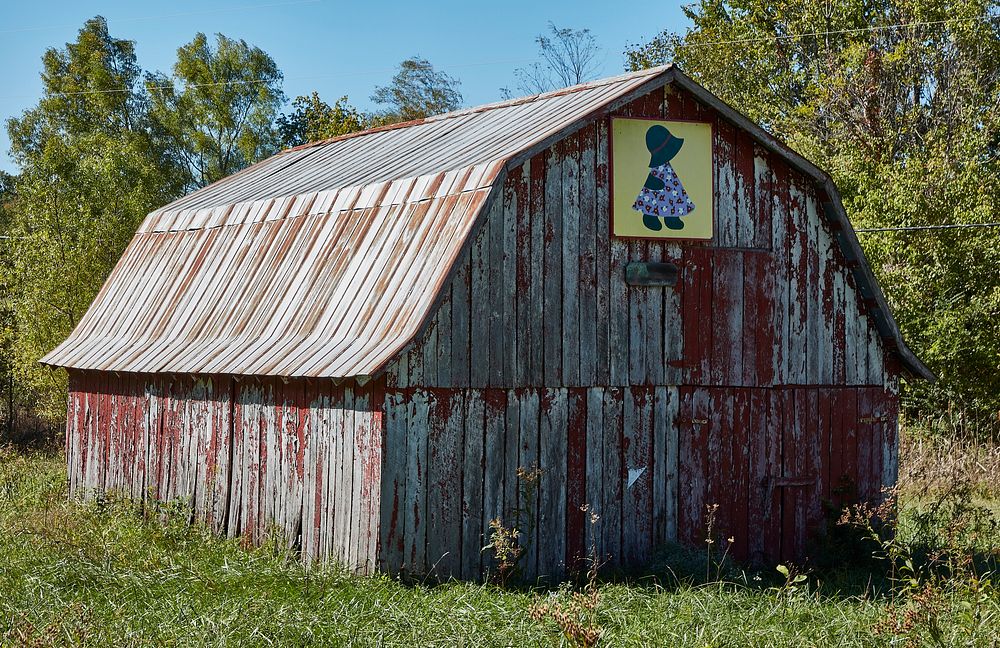                         A "quilt barn" with a painted image of a farm girl similar to one that might be sewn on a quilt, on…