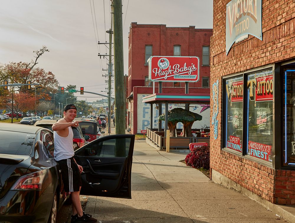                         Scene outside the Victory Tattoo Parlor and Hugh-Baby's BBQ (barbecue) and burger shop along an…