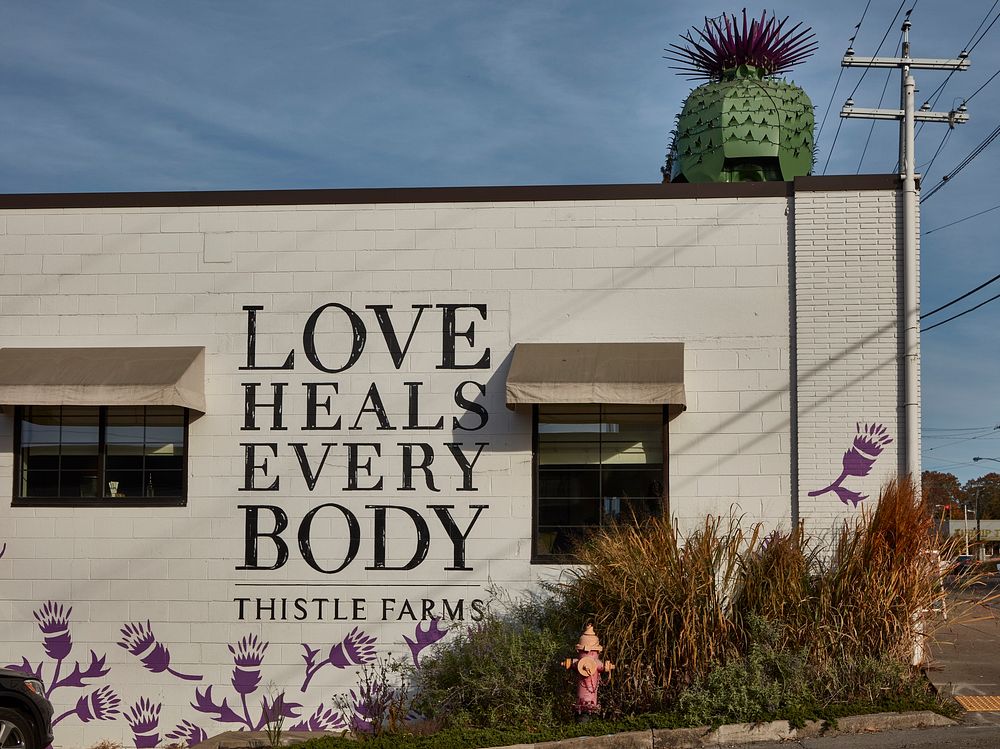                         Sign and thistle figure at the Thistle Farms natural-products boutique along an eclectic strip of…