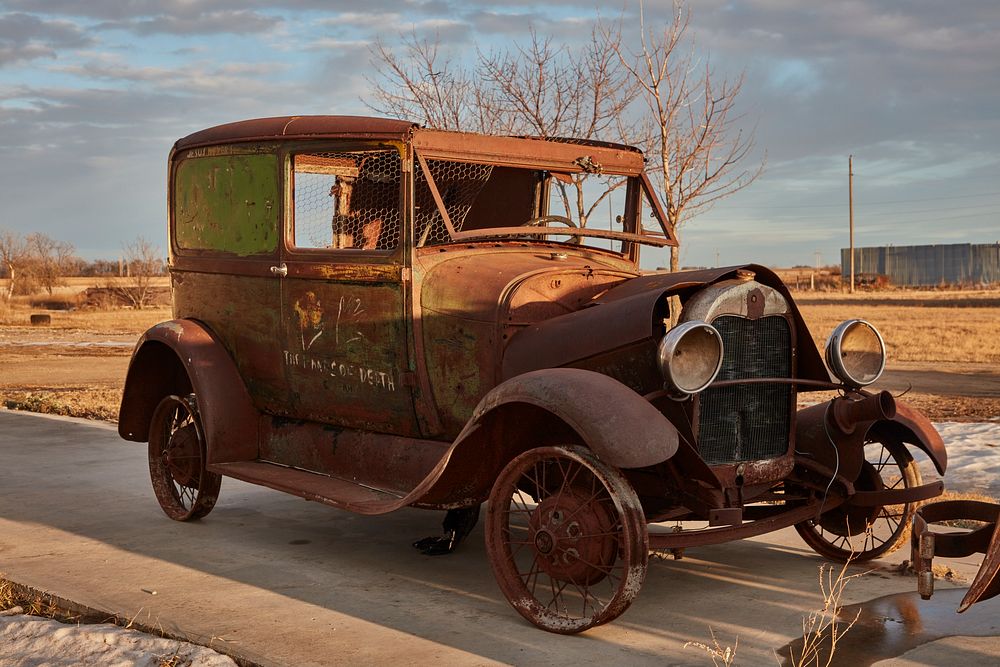                         A very old and rusted automobile, sometimes called a "jalopy" in its fading years, beside the road…