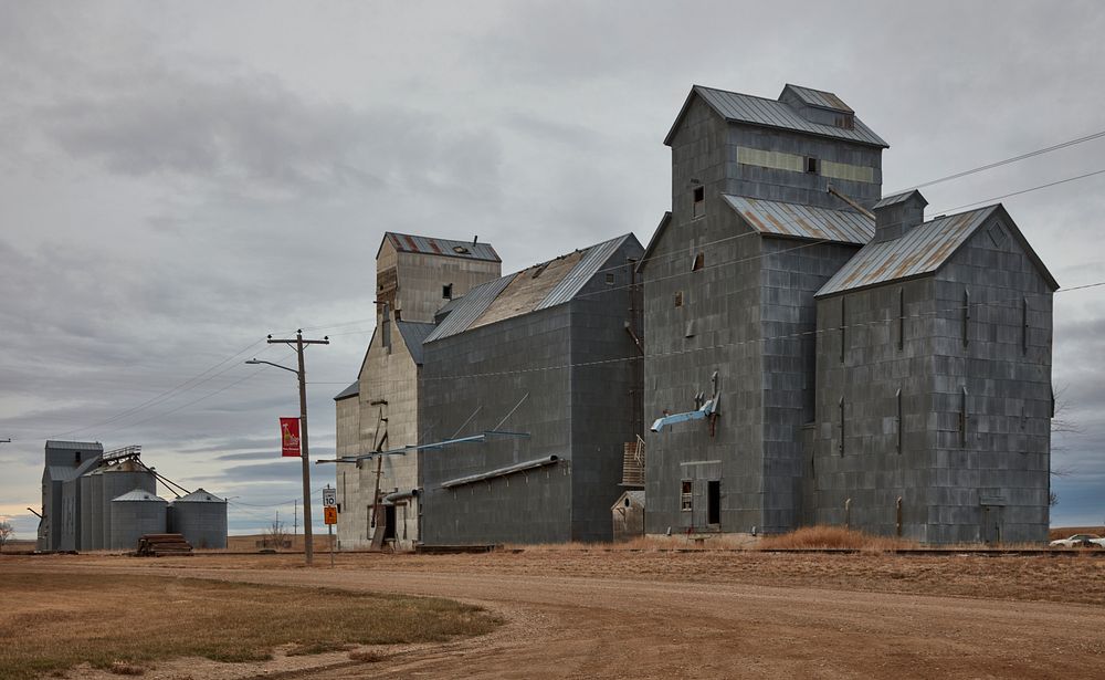                         A weathered grain elevator complex looms over the prairie in the old Great Northern Railroad town of…