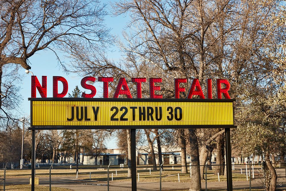                         A sign advertising the fair at the North Dakota State Fairgrounds in Minot (pronounced MINE-ott)…