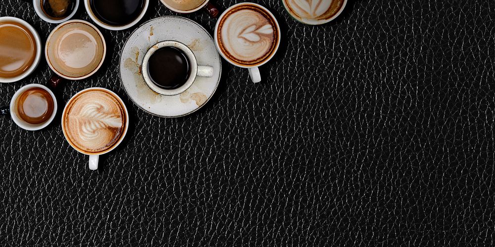 Various coffee mugs on a black leather textured wallpaper