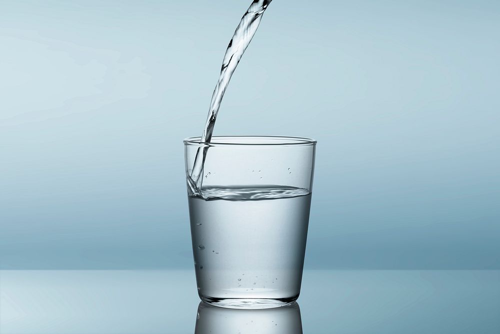 Pouring water in glass, blue background