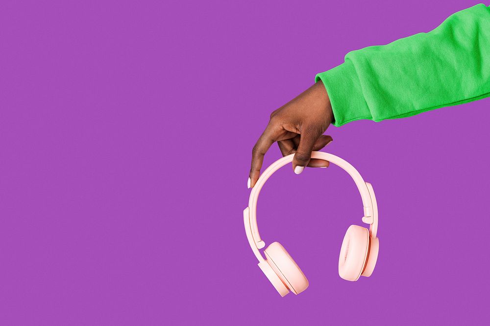 Hand holding wireless pink headphones