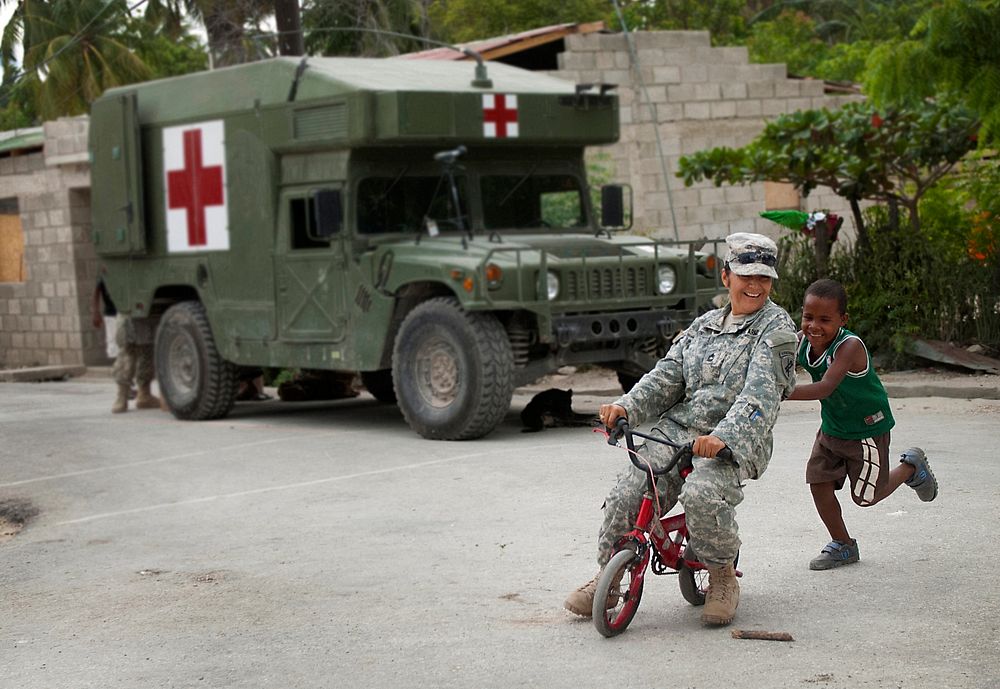 U.S. Army Master Sgt. Elizabeth Limon, with the 486th Civil Affairs Battalion, tries out a boy's bike near the site of a…