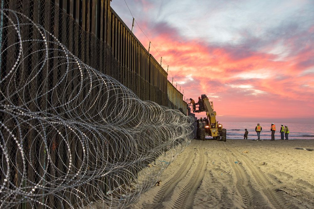 U.S. Border Patrol Agents at Border Field State Park in San Diego watch over personnel reinforcing the border fence with…