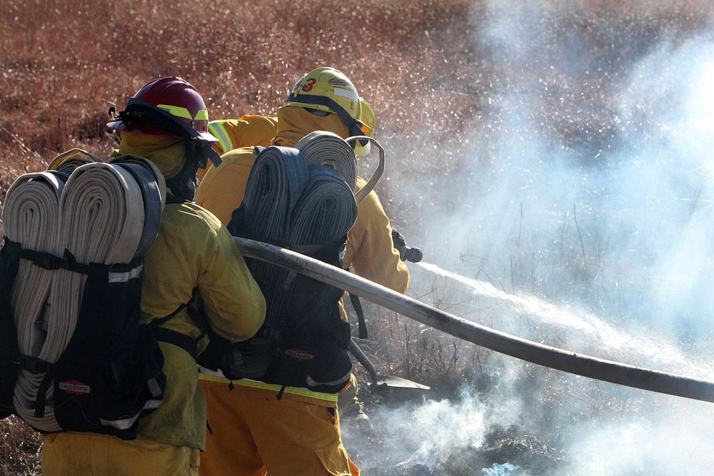 Firefighter, combating flame, water hose. Original public domain image from Flickr