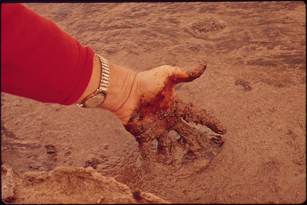 Man touching crude oil in San Juan River, 10/1972. Original public domain image from Flickr