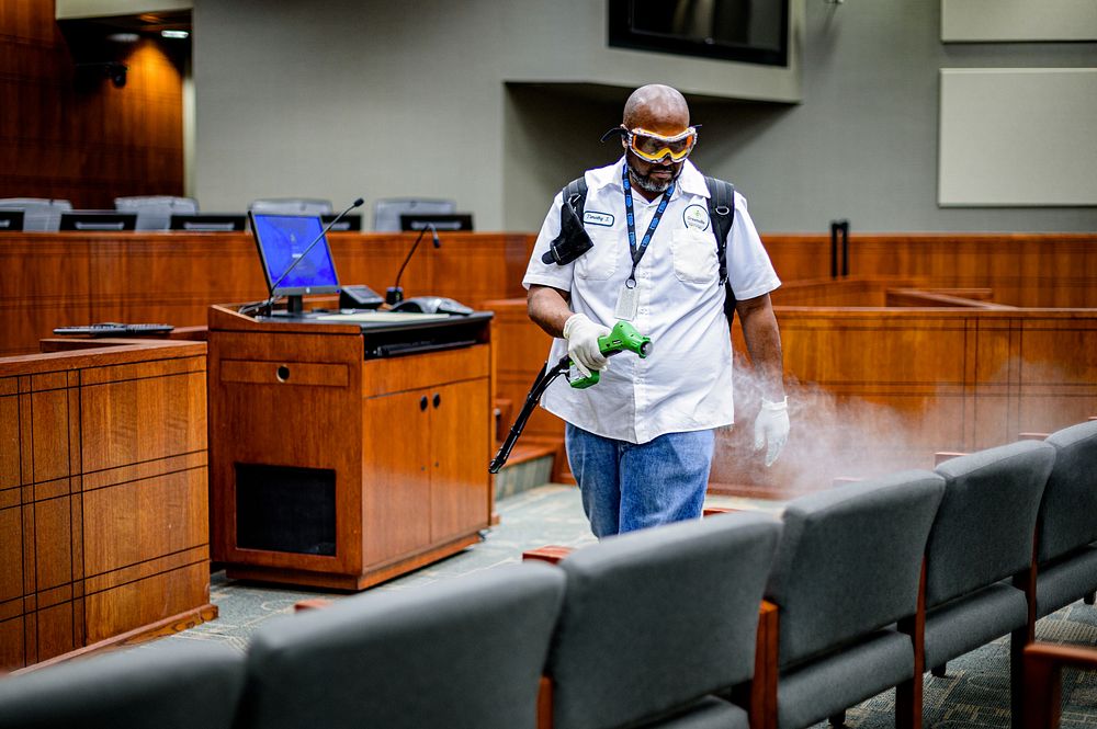 City staff spray disinfectant in the City Hall Council Chambers on Friday, March 20, 2020. Original public domain image from…
