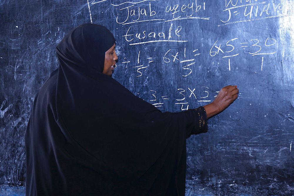 Somalian woman teacher writing on chalkboard. Original public domain image from Flickr
