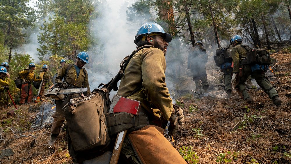 Blue Ridge and Plumas Hot Shots connect after completing a fire-suppressing fire line on a smoky steep-sloped mountain to…