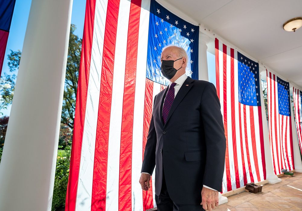 President Joe Biden walks past draped America flags along the Colonnade of the White House, Monday, November 15, 2021, en…