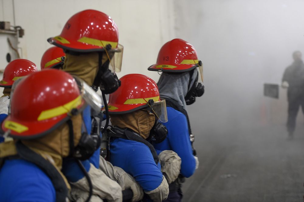 211209-N-YK120-1007 ATLANTIC OCEAN (Dec. 09, 2021) Sailors fight a simulated fire in the hangar bay of the Nimitz-class…