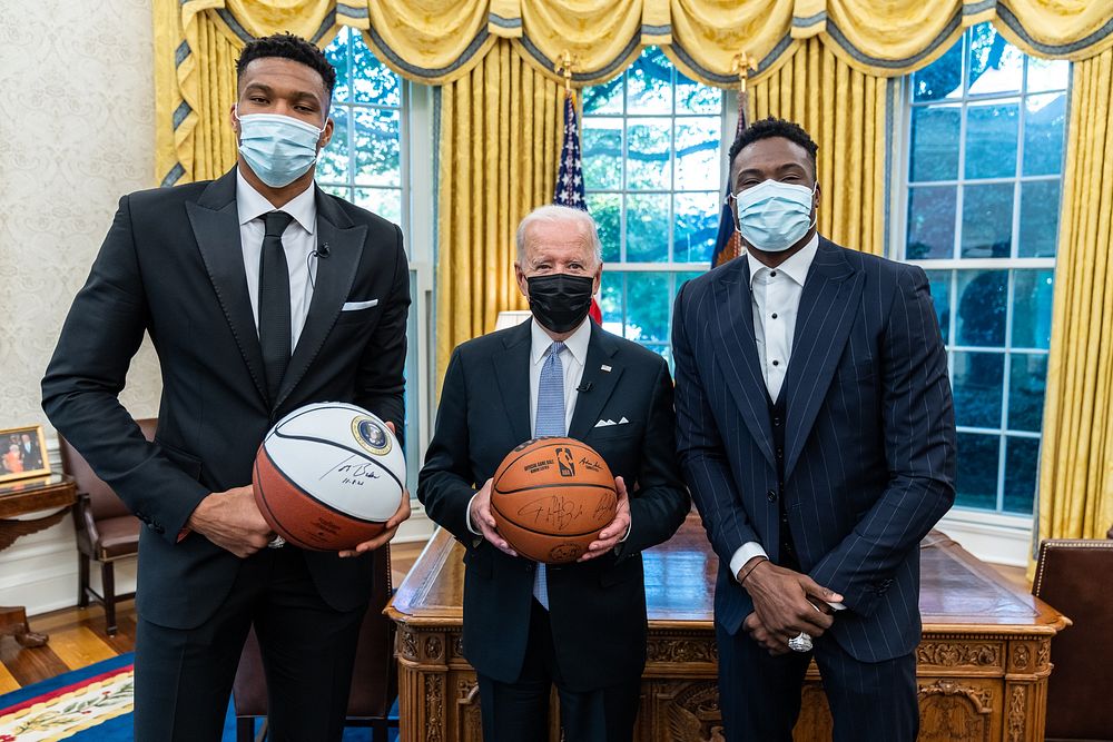 President Joe Biden signs a basketball and records a video message with Giannis Antetokounmpo and Thanasis Antetokounmpo of…