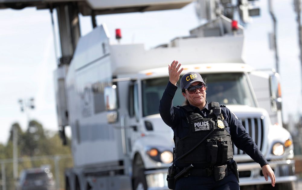 An officer with U.S. Customs and Border Protection Office of Field Operations waves a truck forward to be scanned during Non…