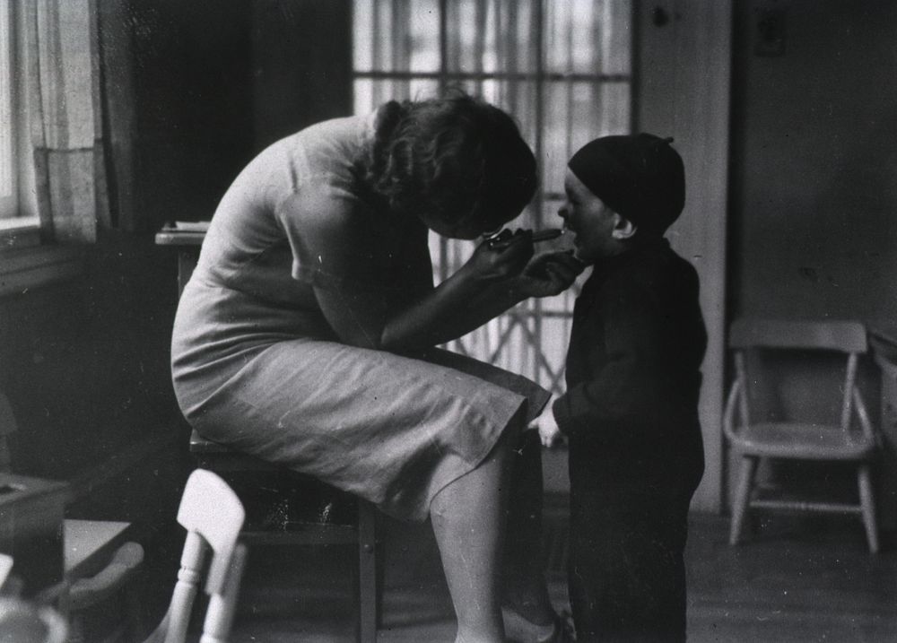 School Nursing. Showing a nurse examining a small boy's throat. Original public domain image from Flickr