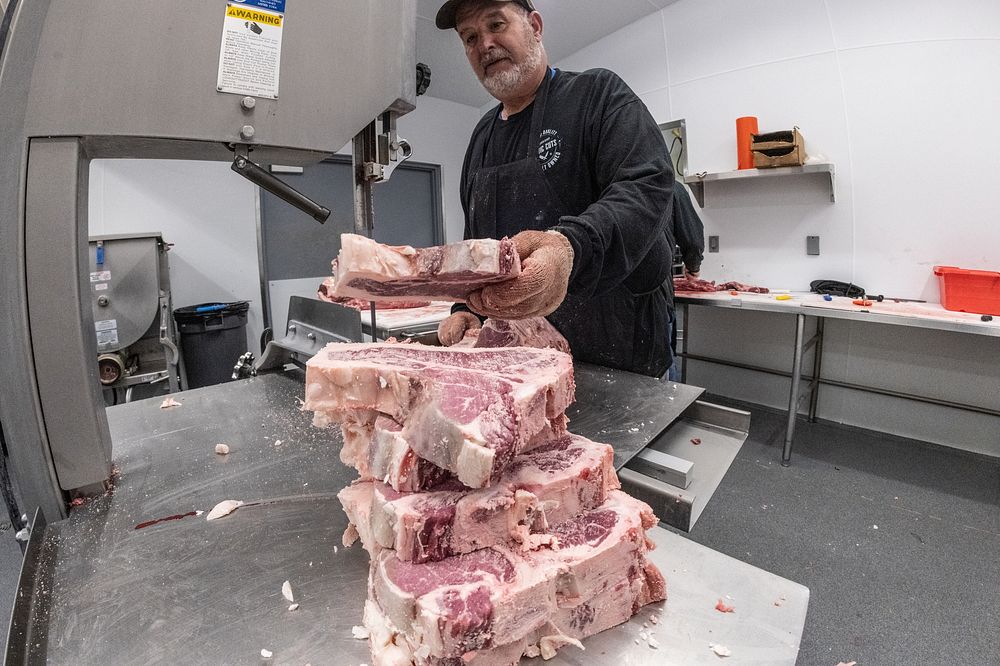 Meat cutter Marty Smith uses a band saw to cut T-bone steaks at Rustic Cuts in Council Bluffs, IA, on July 9, 2021. Original…