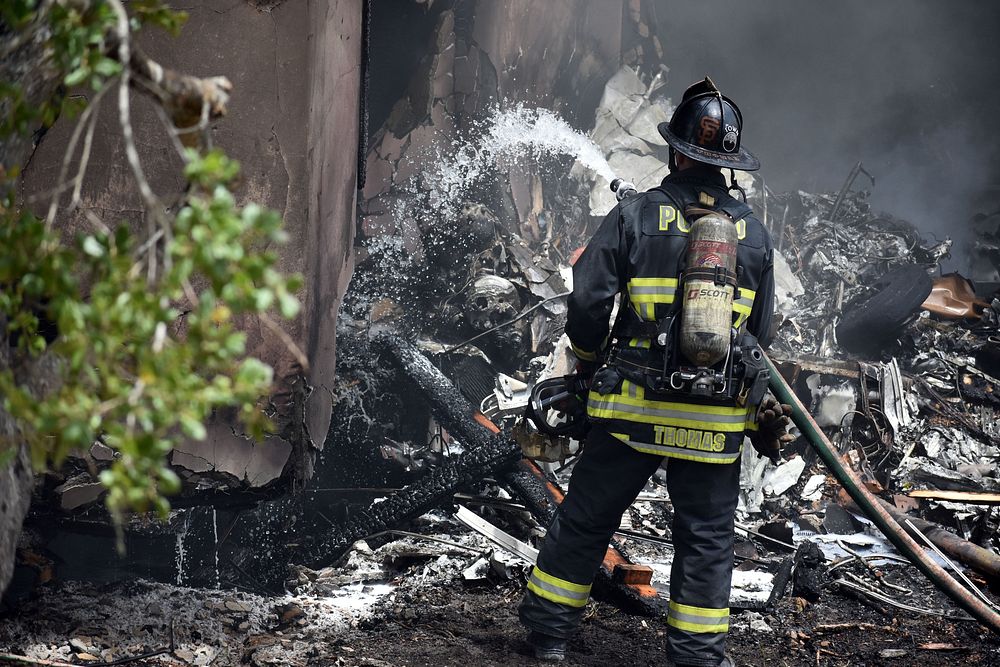 Firefighter extinguishing fire. Original public domain image from Flickr