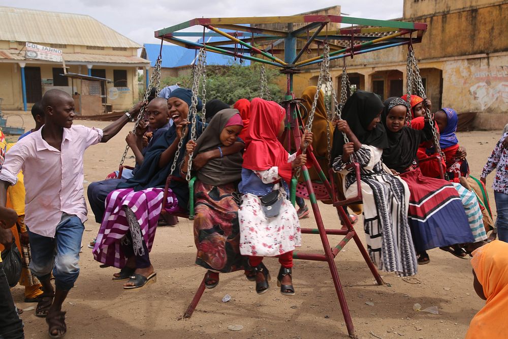Children play on swings at playground on Eid al-Adha day. AMISOM Photo. Jowhar, Somalia, July 20, 2021. Original public…