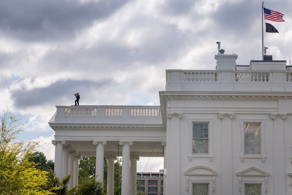 A U.S. Secret Service Counter Assault Team agent is seen on top of the White House. Original public domain image from Flickr