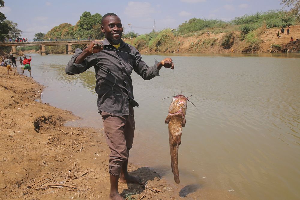 Somalian man caught a fish by the lake. Original public domain image from Flickr