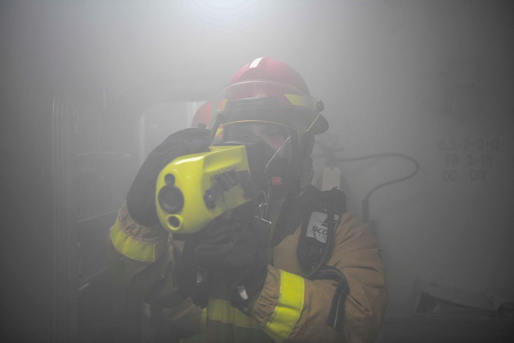 Machinery Repairman 3rd Class Alec Schwarz uses a naval infrared thermal imager (NIFTI) to search for hot spots during a…