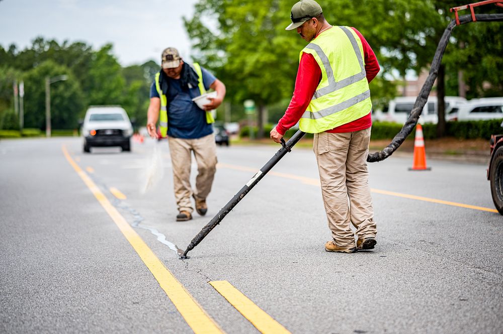 Pavement crack sealing being performed along Red Banks Road, Greenville, June 14, 2022. Original public domain image from…