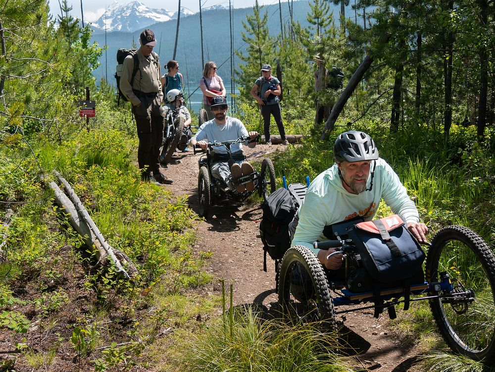 Hiking the Rocky Point TrailA group of people hike along the Rocky Point Trail, some using mobility devices like handcycles.…