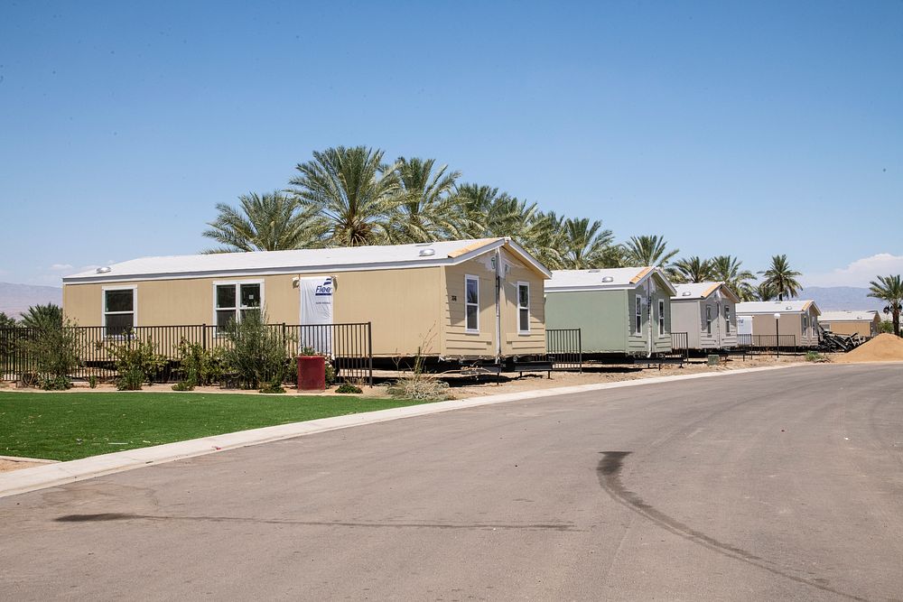 Double-wide mobile homes in various stages of being joined, set, secured on a foundation and finished for new occupancy at…