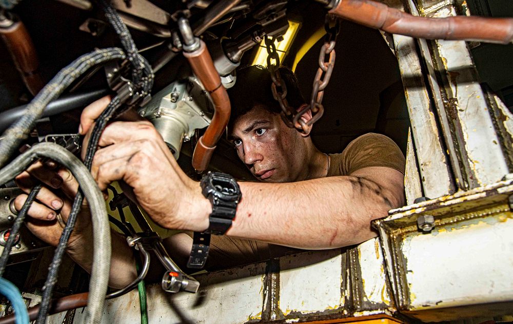 Aviation Machinist&rsquo;s Mate Airman Brendon Harper, from Lusby, Maryland, removes harnesses from a jet engine in the jet…