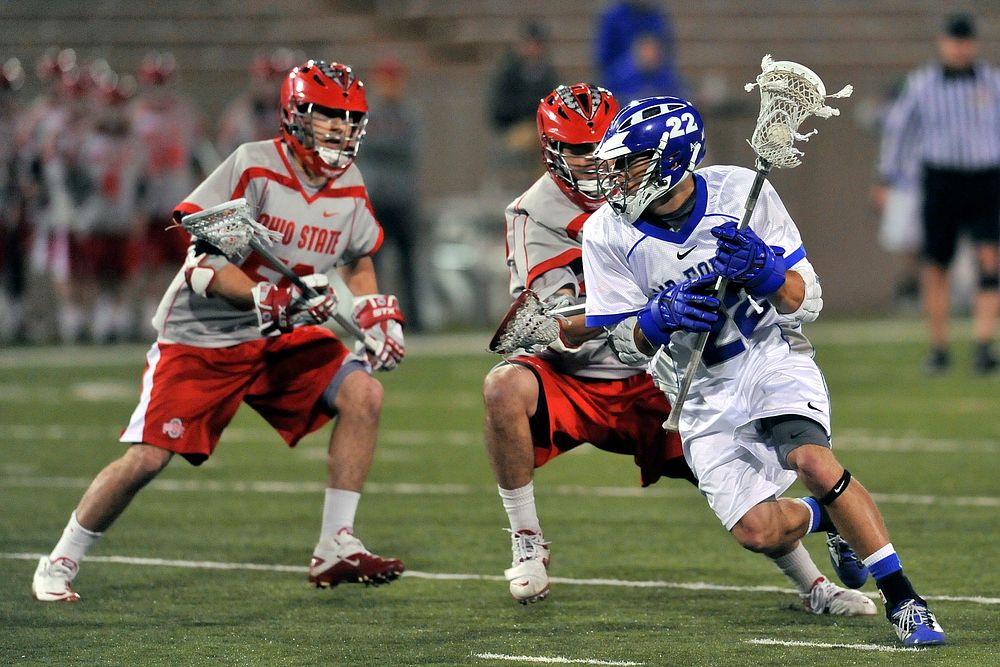 Adam Paranka, a junior attacker on the U.S. Air Force Academy Falcons lacrosse team, in blue, maneuvers around Ohio State…