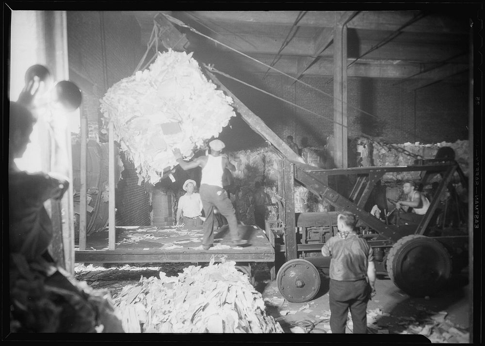 Longshoremen. Large bale being lifted by crane and directed by man on platform, July 1937. Photographer: Hine, Lewis.…