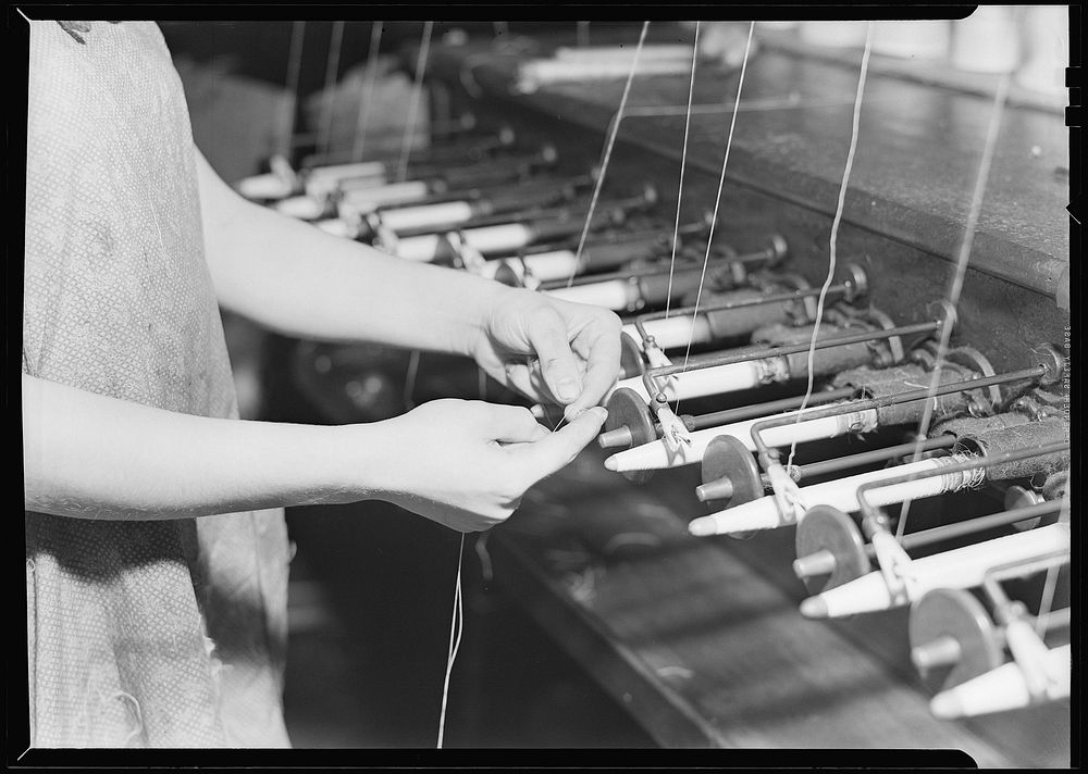 Quiller tying the broken ends of thread being wound on to quills, March 1937. Photographer: Hine, Lewis. Original public…