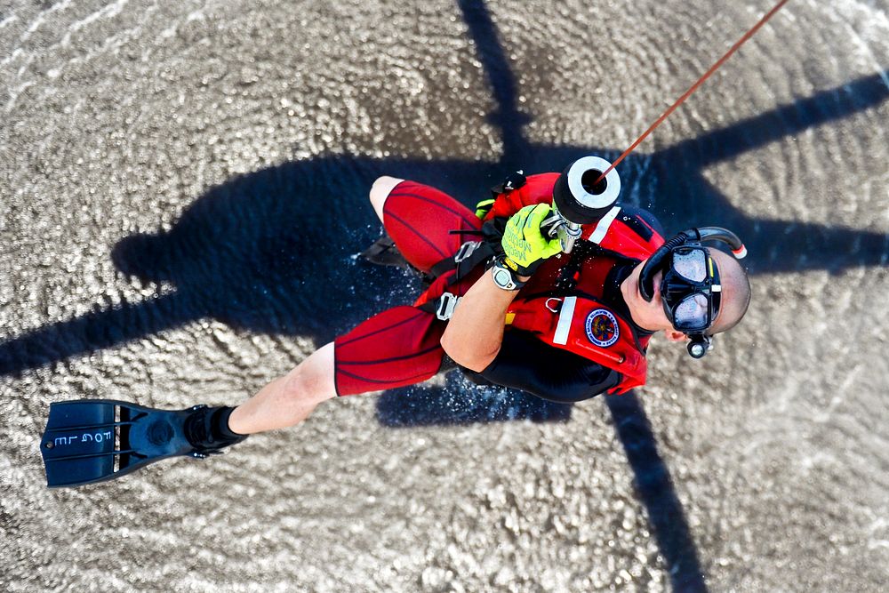 U.S. Coast Guard Petty Officer 1st Class Bret Fogle, a rescue swimmer, is hoisted into an MH-60 Jayhawk helicopter at Coast…