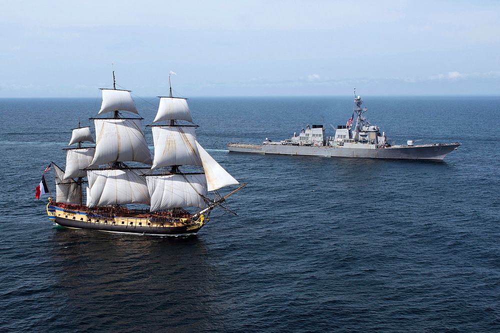 The Arleigh Burke-class guided-missile destroyer USS Mitscher (DDG 57), right, provides a warm welcome to the French tall…