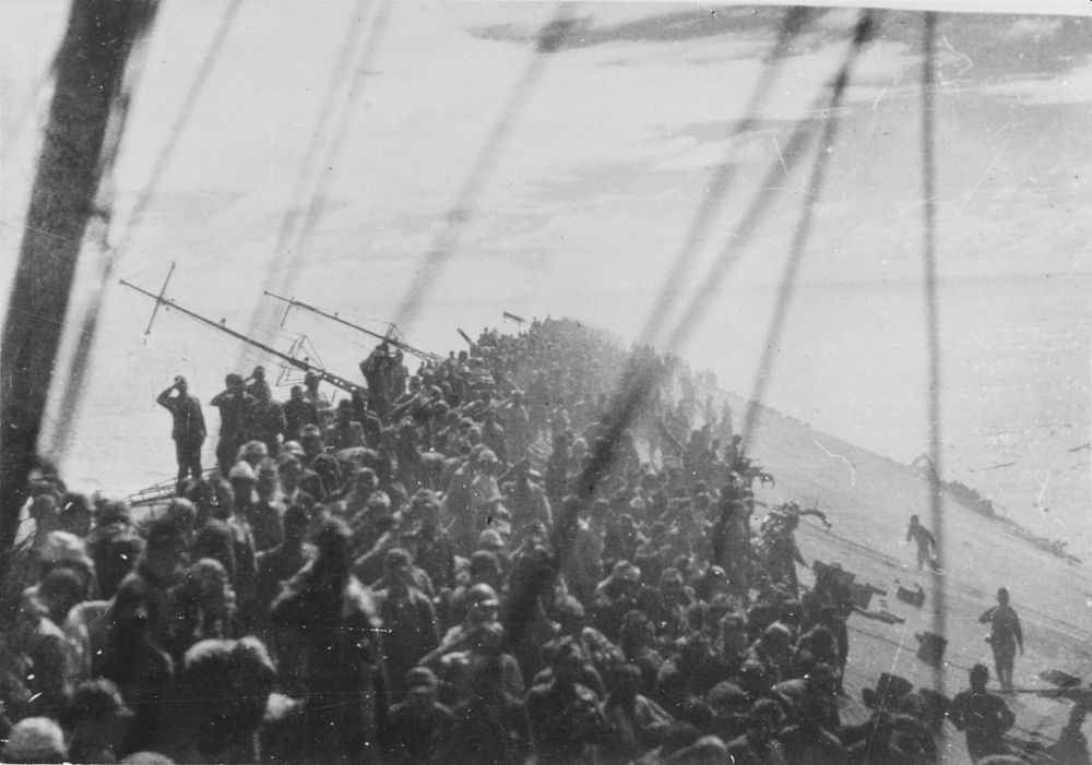 The crew of the Japanese aircraft carrier Zuikaku salute as the flag is lowered during the Battle off Cape Engaño, October…