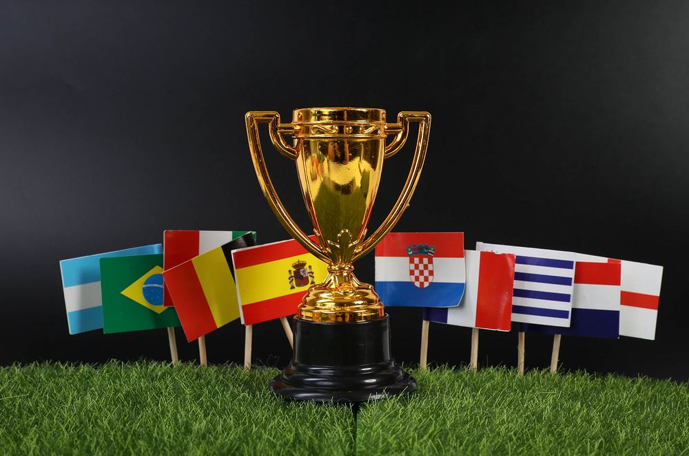 Golden trophy with national flags on grass   