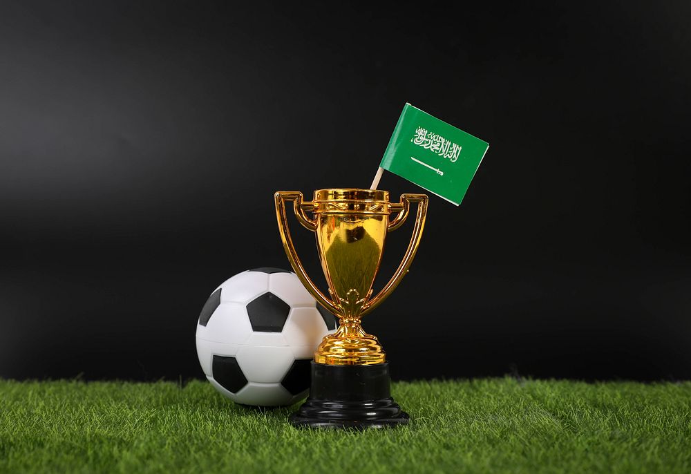 Golden trophy and football ball with flag of Saudi Arabia 