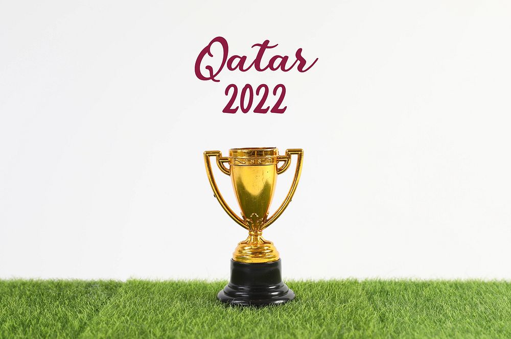 Golden trophy with Qatar 2022 text on green grass 