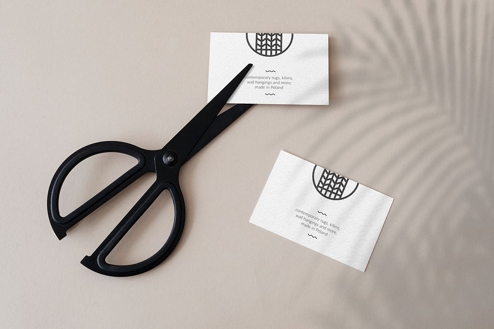 White business cards with scissors on a concrete wall mockup
