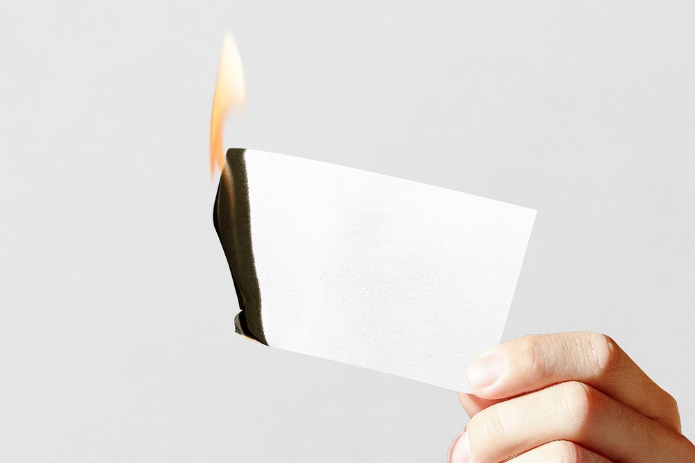 Hand holding burning white card