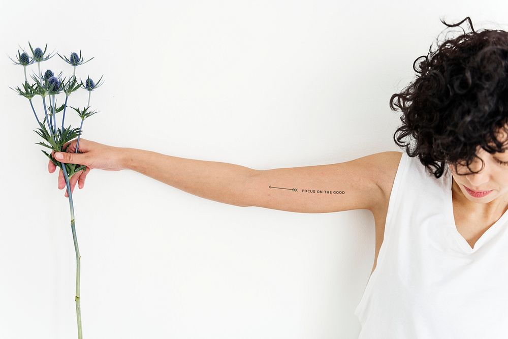 A woman is showing her tattoo on her arm