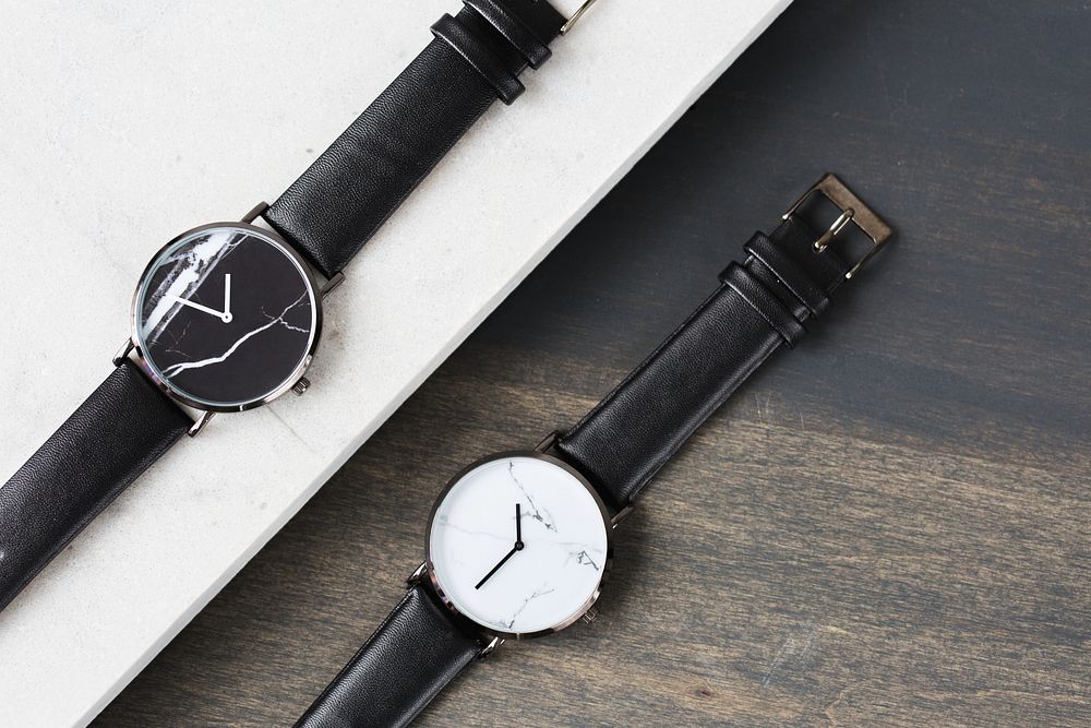 A pair of watches with with black straps and a marble finish on the watch face.