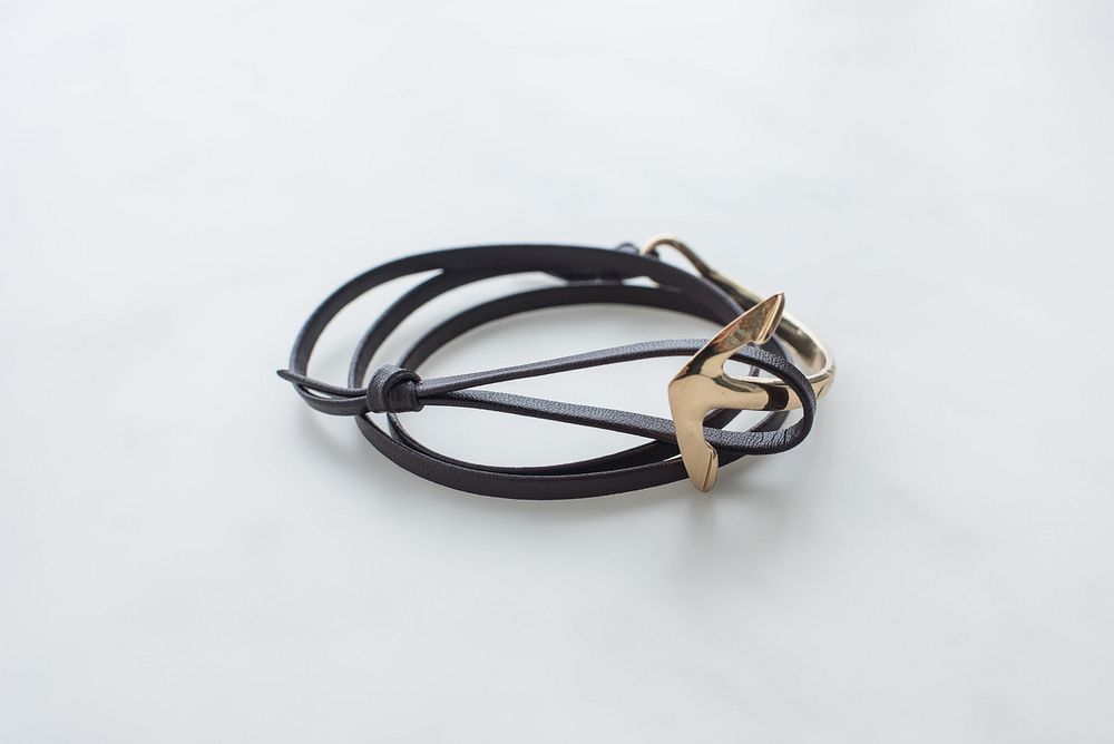 Black leather bracelet with gold anchor.
