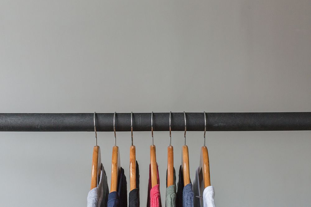 Close up of 7 wooden hangers with t-shirts hanging up.