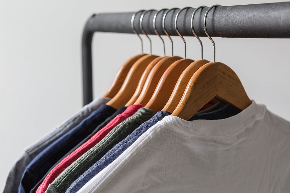 T-shirts hanging on wooden hangers.