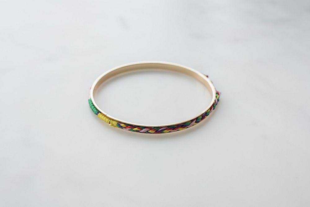 Silver bracelet with multicolored thread embroidering.